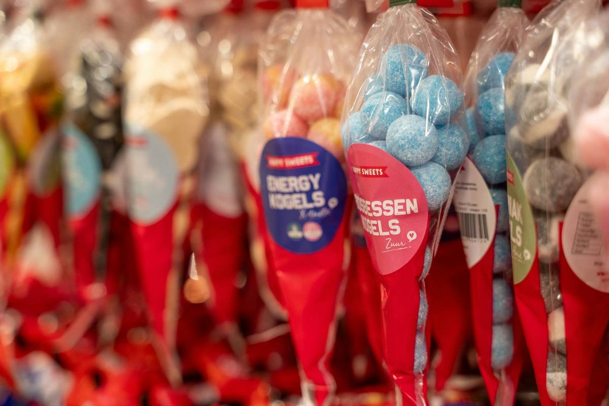 hand using candy cane spoons individually wrapped to stir molten sugar in saucepan